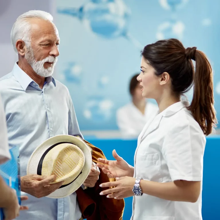 Senior man and female doctor talking to each other in a lobby at medical clinic.